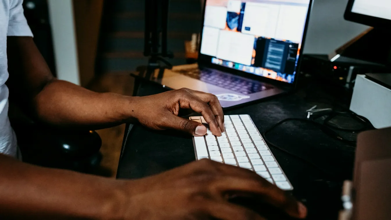 a man typing on a keyboard in front of a computer