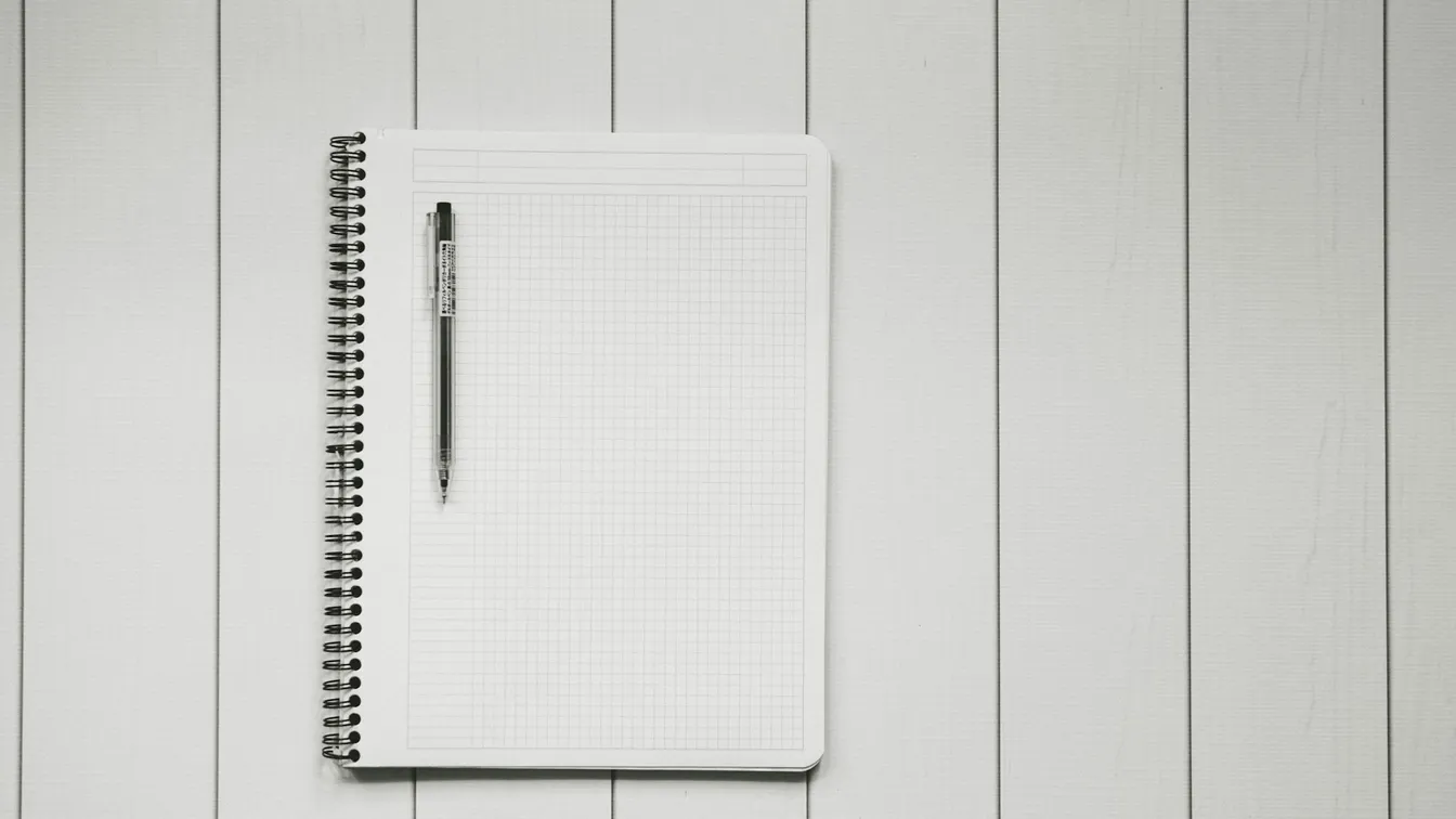 a notebook with a pen on a wooden background