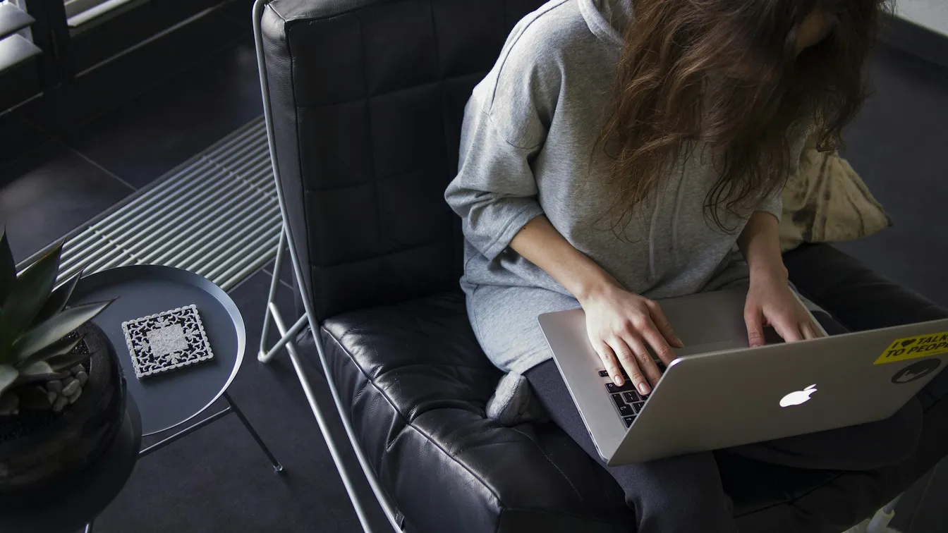 a woman sitting in a chair using a laptop